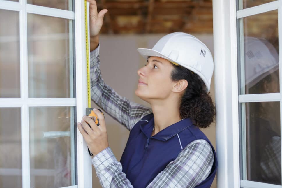 double glazing installer measuring an open white window