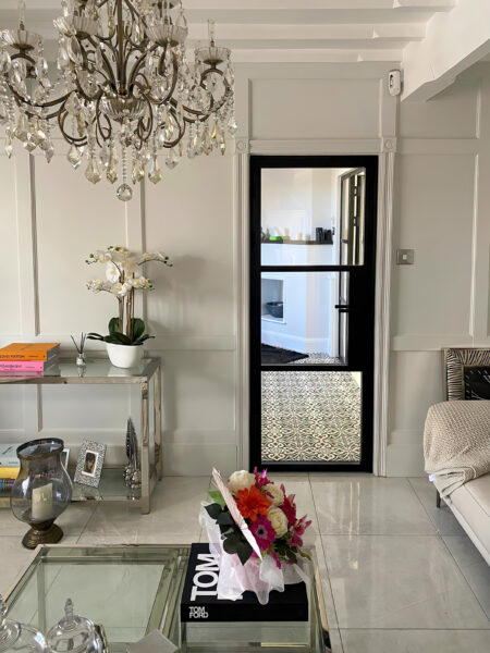 single black metal door in a lounge with chandelier one of the latest window and door trends