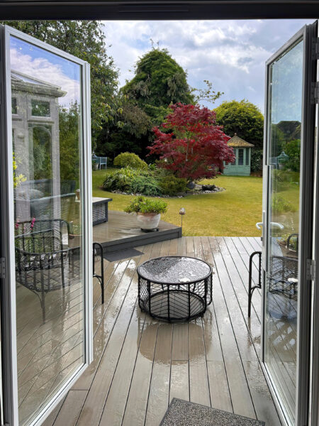 open white patio doors leading out to garden and wet decking slabs