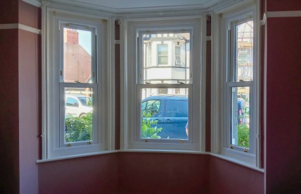 ecoslide upvc  sash windows internal view with maroon walls looking out onto a street. 