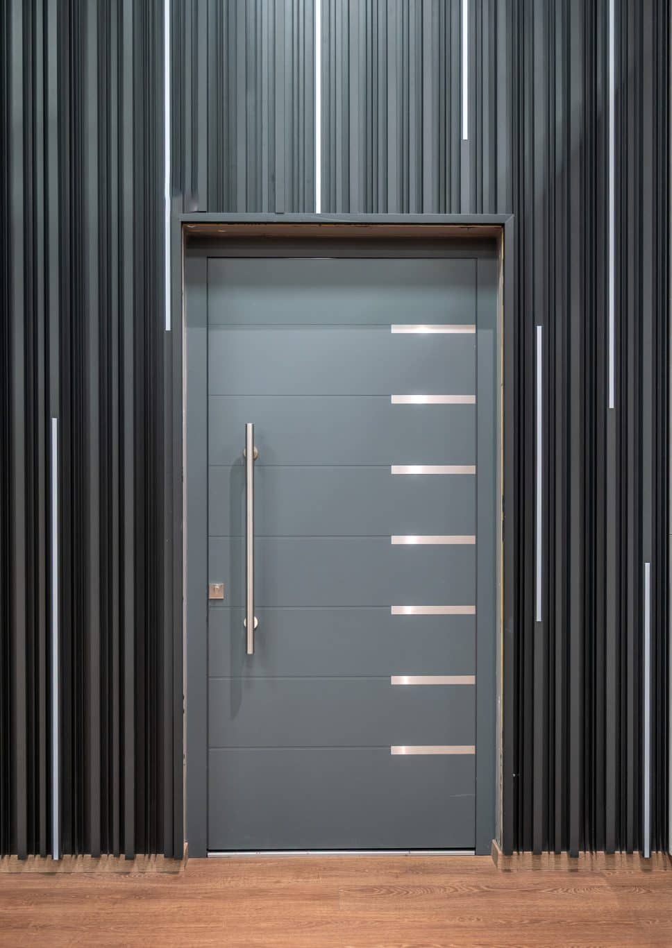 grey alumil front door in a showroom setting with dark grey cladding