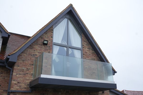 essex house with gable feature window and french doors in front of glass balcony.