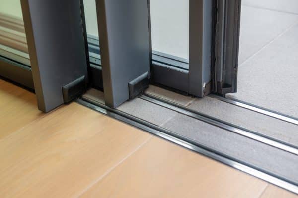 close up picture of three panel sliding door fully open with a flush floor tiled track