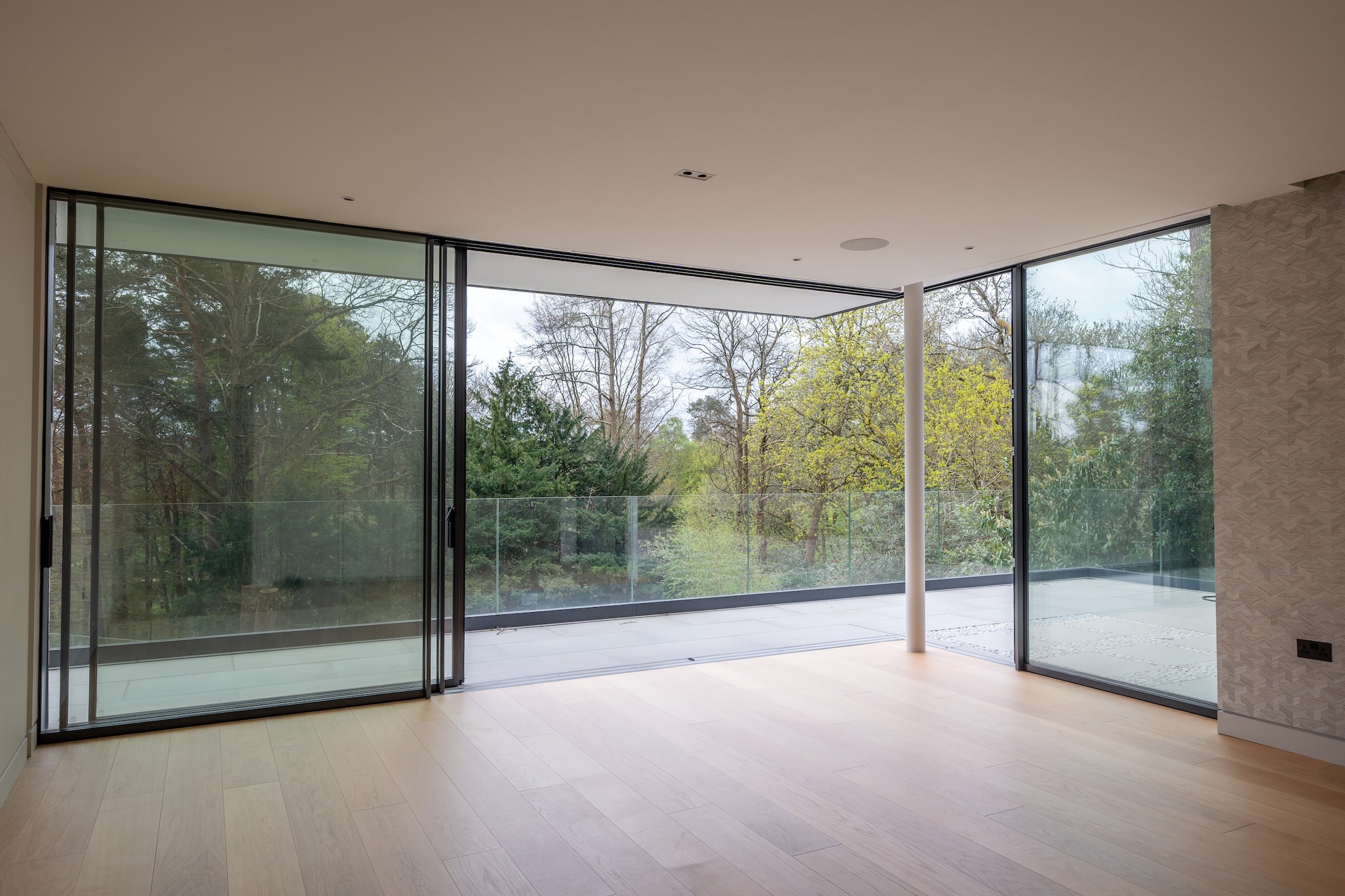 luxview slide 54 open corner sliding doors in an empty room with wood floors and forest views.
