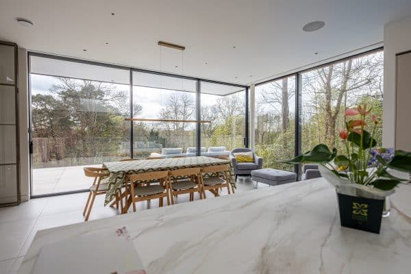 slimline sliding doors and in a contemporary kitchen with  balustrade and forest views