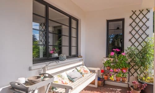 outside view of classic steel look tripe and single window with plants and garden bench
