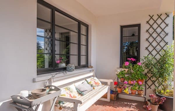 outside view of classic steel look tripe and single window with plants and garden bench