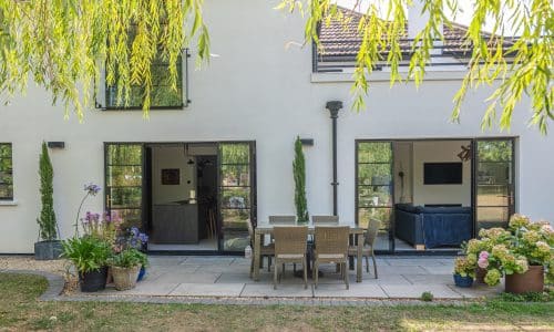 fully open aluco french doors in a rear house extension with garden furniture and plants