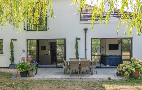 fully open aluco french doors in a rear house extension with garden furniture and plants